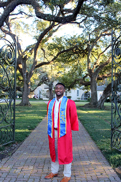 Andre Pittman poses in front of the Alumni Center for grad photos.