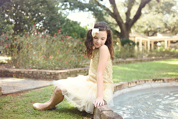 A young girl poses for a photo by the fountain located in the Alumni Center rose garden