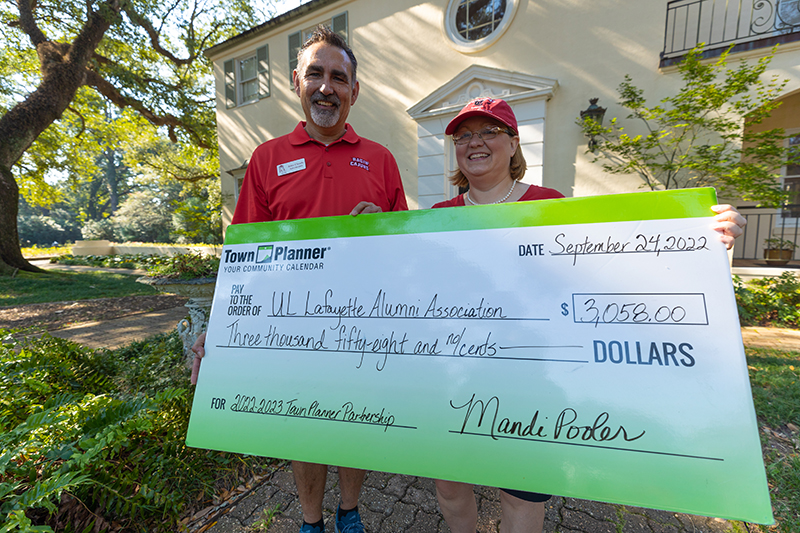 Town Planner's Mandi Pooler presents John Claude Arceneaux with the Alumni Association's proceeds.